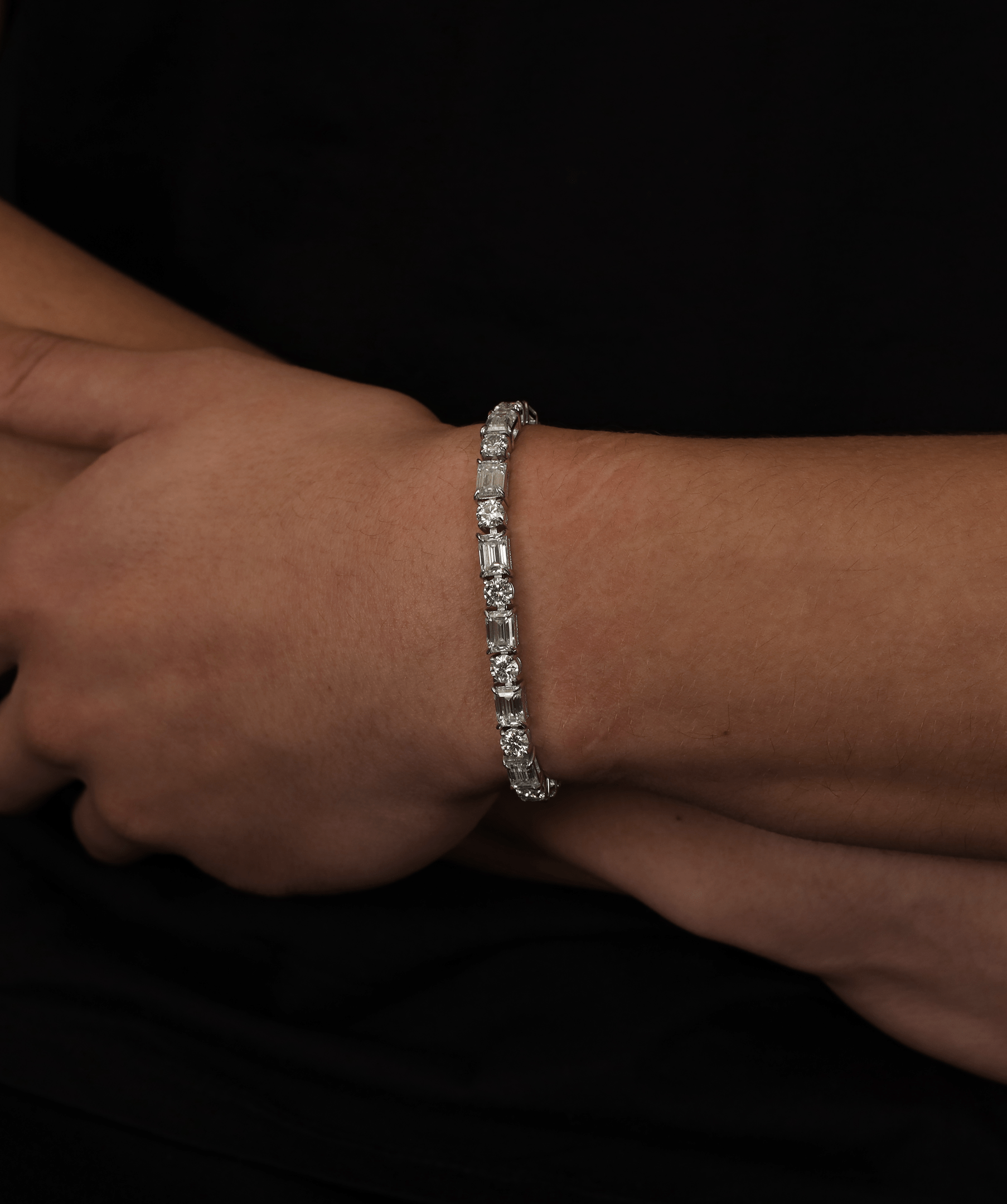 ICED London diamond tennis bracelet on a wrist, close-up jewelry shot against a dark background.