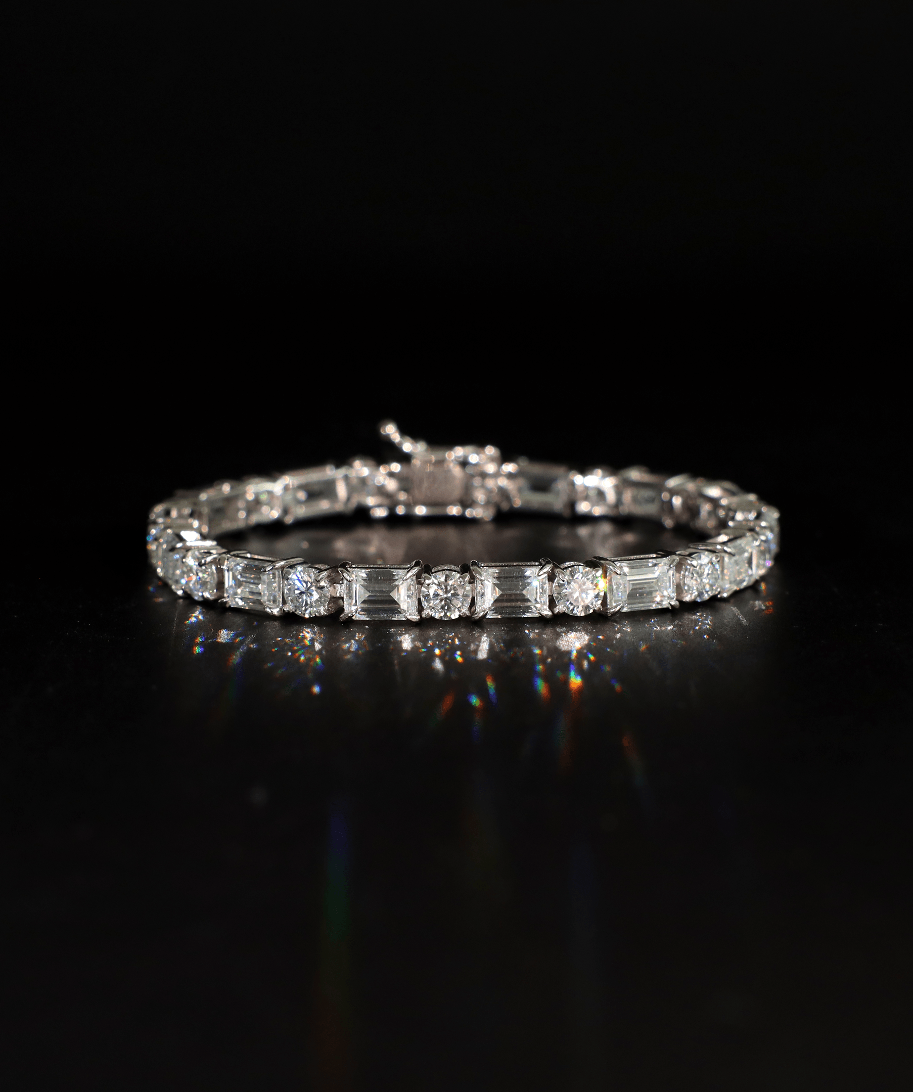 ICED London diamond bracelet with alternating baguette-cut and round diamonds on a silver band, on a black background.