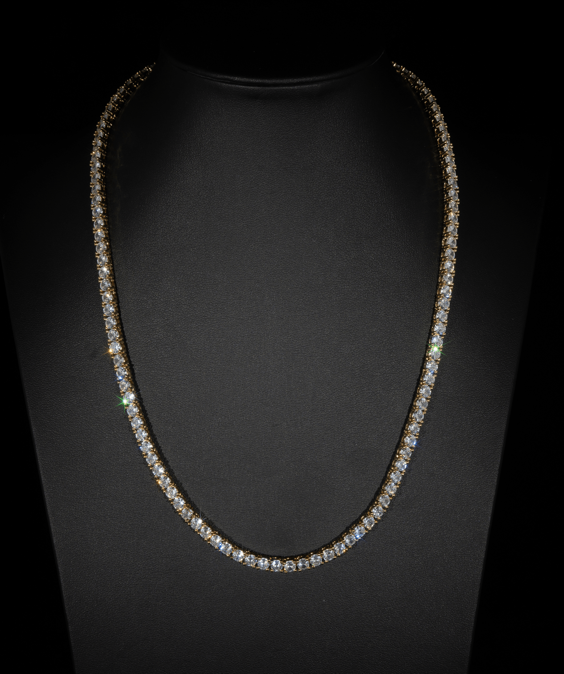 ICED London diamond tennis necklace on a black display, gold setting with sparkling stones.