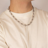 ICED London silver bead chain necklace on a man’s white crew-neck T-shirt, close-up of neck and chin.