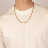 ICED London rose gold chain necklace worn on a cream t-shirt, close-up of neckline.