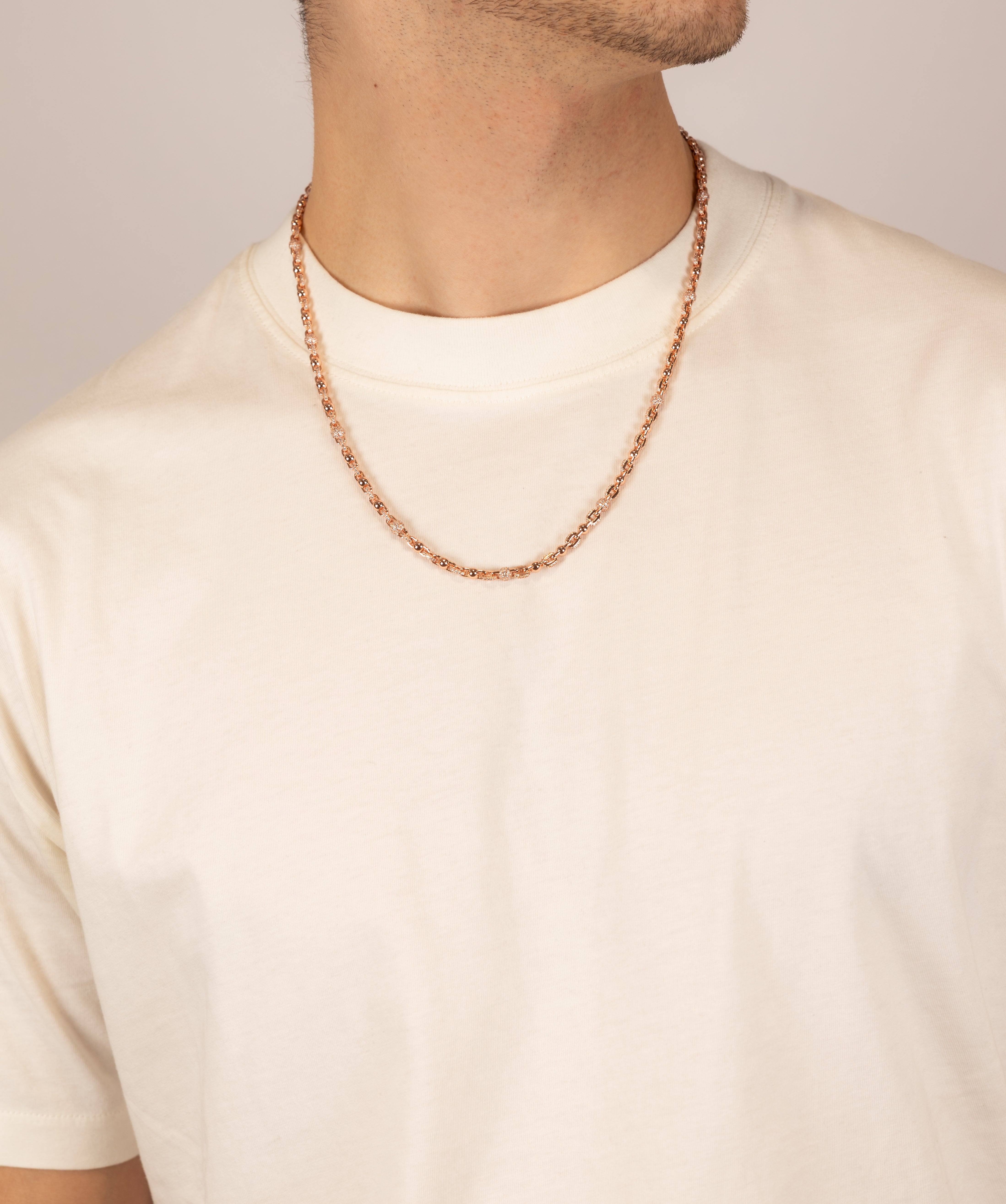 ICED London rose gold chain necklace worn on a cream t-shirt, close-up of neckline.