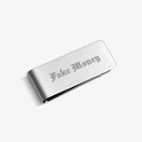 ICED London metal wallet with brushed steel finish, engraved "Fake Money" in Gothic font, minimalist cash-clip design.
