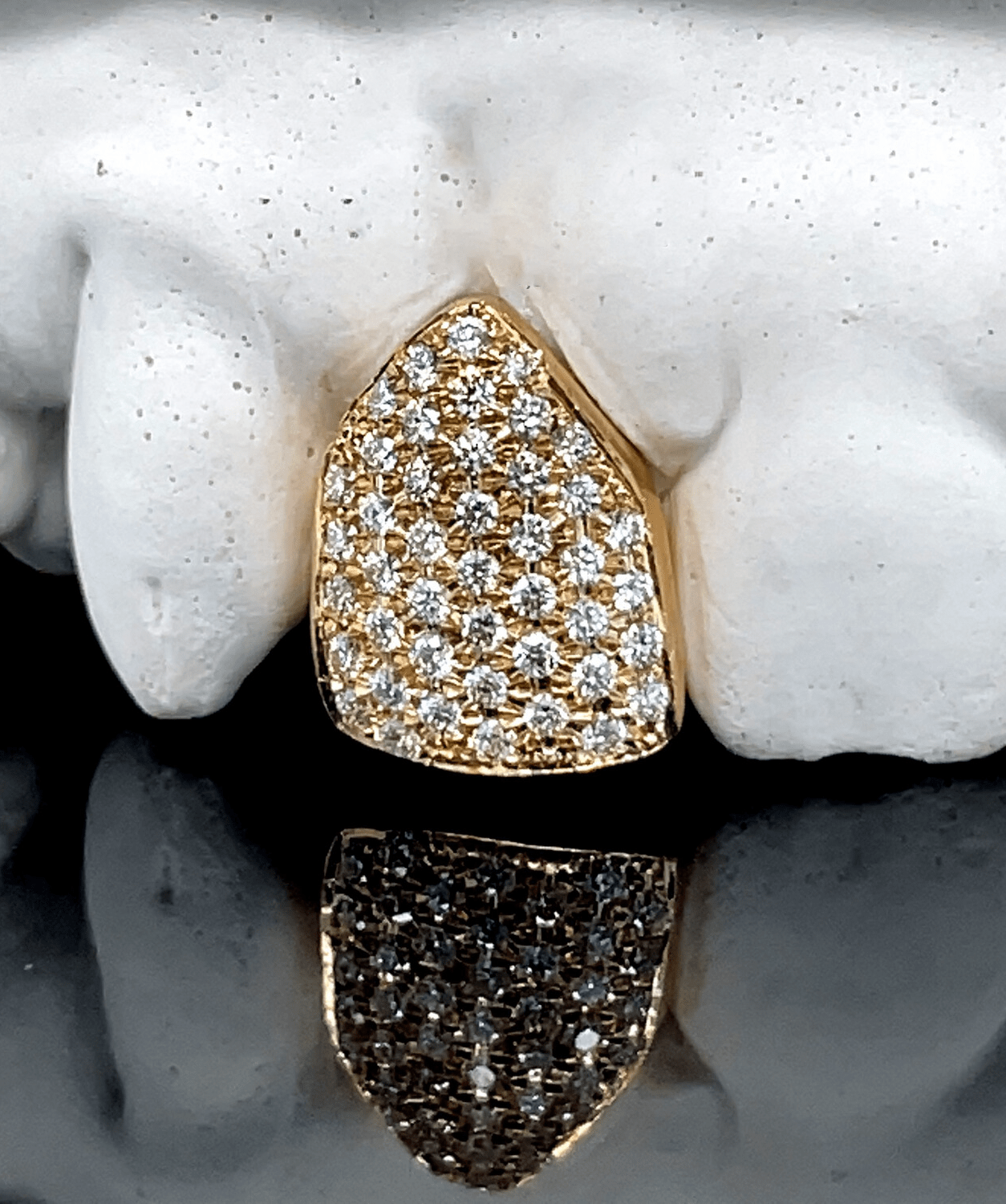 ICED London gold shield-shaped pendant with pavé diamonds, diamond-encrusted Jewelry, reflected on glossy surface.