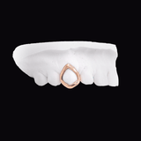 Rose gold teardrop ring placed on a white dental impression against a black background. ICED London.